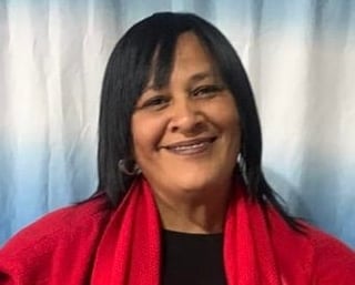 Woman with long black hair wearing a red scarf over a black shirt, smiling at camera against a blue and white textured background